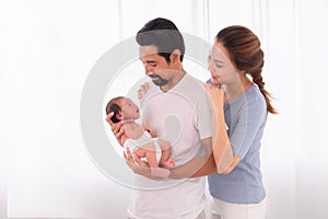 Excited Asian father with beard hold his first child newborn with strong arm, beautiful wife play with baby and try to help