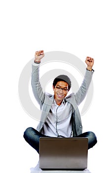 Excited Asian man using laptop on the floor