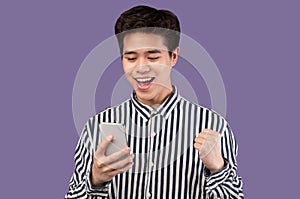 Excited asian man using mobile phone, celebrating online win