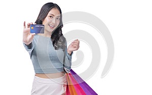 Excited asian showing credit card holding shopping bags in arm standing white background. Cheerful shopper girl using plastic card