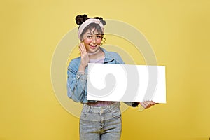 Excited Asian teen girl holding blank speech bubbles on yellow background