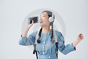 Excited asian woman posing isolated over white background listening music with headphones dancing singing