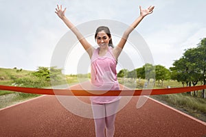 Excited asian woman runner crossing the finish line of a marathon