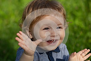 Excited baby on the meadow field. Toddler child walking outdoor, family vacations, summer season nature. Baby face close