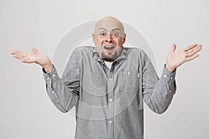 Excited bald male with beard in casual shirt exclaiming, looking at camera in amazement with opened mouth, clapping