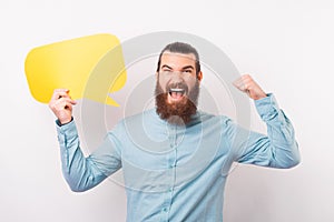 Excited bearded man is making the winner gesture and holding a speech bubble.