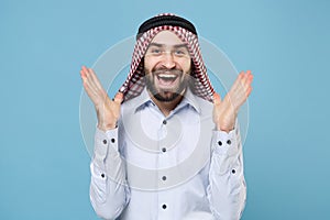 Excited bearded young arabian muslim man in keffiyeh kafiya ring igal agal casual clothes isolated on pastel blue photo