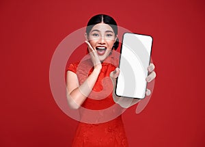 Excited Beautiful chinese Asian woman holding smartphone mockup of blank screen and smiling isolated on red background