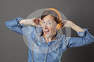 Excited beautiful middle aged woman laughing with funky music on