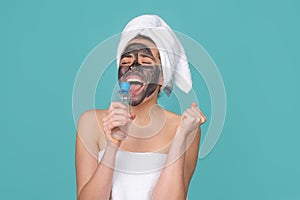 Excited beautiful woman with cosmetic mud facial procedure, spa health concept. Skin care beauty treatment. Towel on