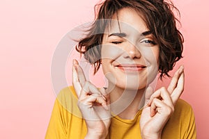 Excited beautiful woman posing isolated over pink wall background make hopeful please gesture fingers crossed