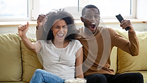 Excited biracial couple have fun watching sports game together