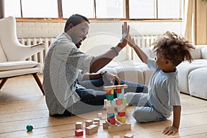 Excited biracial dad and son give high five playing