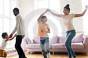 Excited biracial family with kids have fun dancing at home