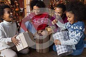 Excited biracial family unpack Christmas gifts together