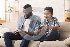 Excited Black Boy Playing Video Games With Dad At Home