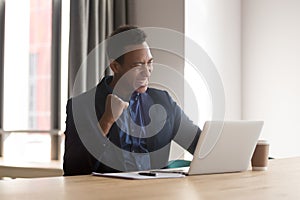 Excited black businessman feel euphoric reading good news online