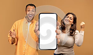 Excited Black Couple Demonstrating Big Smartphone With White Screen And Celebrating Success,
