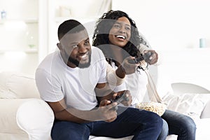 Excited black couple enjoying video game, competing with each other