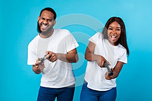 Excited black couple playing video games together with joysticks