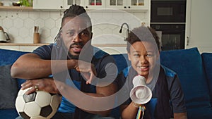 Excited black family of football fans watching match on tv and cheering team