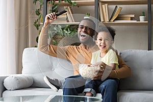 Excited black father with toddler son watching sport tv game