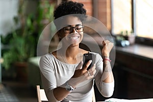 Excited black girl feel euphoric reading news on cell