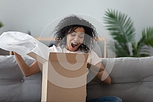 Excited black girl feel overjoyed opening package at home