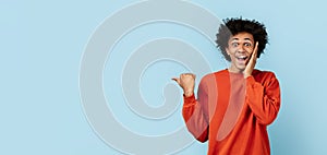 Excited black guy pointing with thumb on blue background