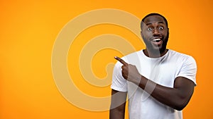 Excited black man pointing finger into background, template for text, attention