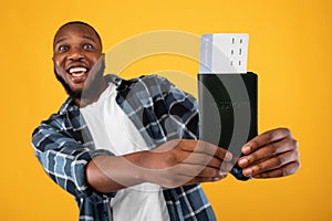 Excited Black Man Showing Travel Tickets Posing Over Yellow Background