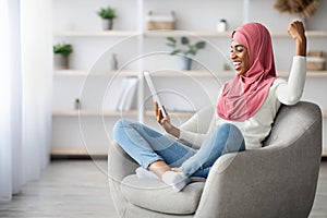 Excited Black Muslim Woman Looking At Digital Tablet And Exclaiming With Joy