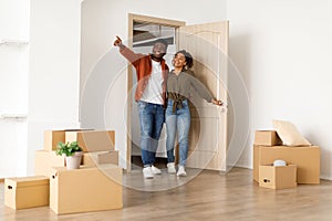 Excited Black Spouses Entering Their New Home, Husband Pointing Aside