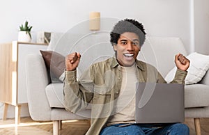 Excited black teen guy watching sports game on laptop computer at home, copy space