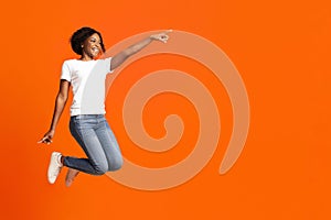 Excited black woman jumping up and showing copy space