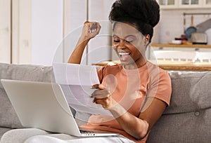 Excited Black woman sit on sofa at home receiving job enjoy exam results or college admission letter