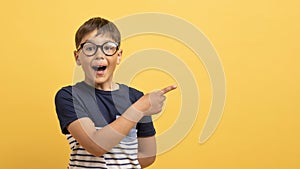 Excited boy in casual t-shirt pointing at copy space