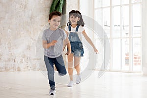 Excited boy and girl have fun running in empty room