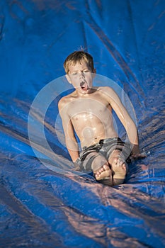 Excited boy playing on a slip and slip outdoors