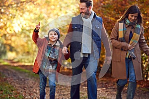 Excited Boy Ponting On Family Autumn Walk Through Countryside With Parents