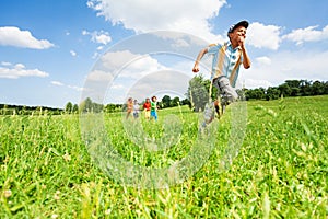 Excited boy runs away from his mates in field