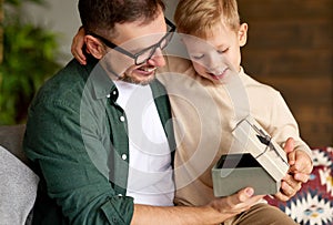 Excited boy son receiving gift box from young loving father on holiday