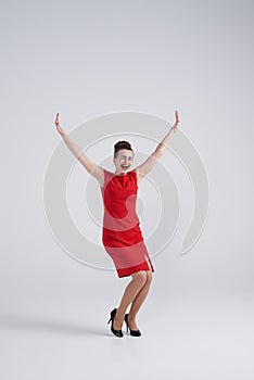 Excited brunette in red dress outstretching hands