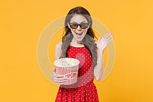 Excited brunette woman girl in red summer dress, 3d glasses isolated on yellow background. People lifestyle concept