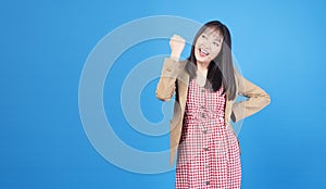 Excited business asian woman holding fist arms hand smile happiness success job or lucky standing over  blue background.