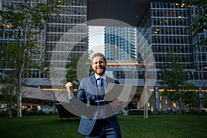 Excited business man. Business man standing in the the city is happy to succeed in his work. He lifts his arms up.