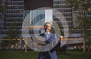 Excited business man. Business man standing in the the city is happy to succeed in his work. He lifts his arms up.