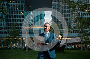 Excited business man. Business man standing in the the city is happy to succeed in his work. He lifts his arms up.