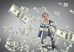 Excited business man looking at money rain against grey background