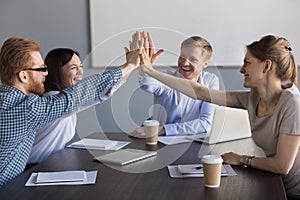 Excited business team of employees giving high five during meeti